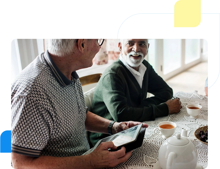 Two older men sitting at a table with tea cups.