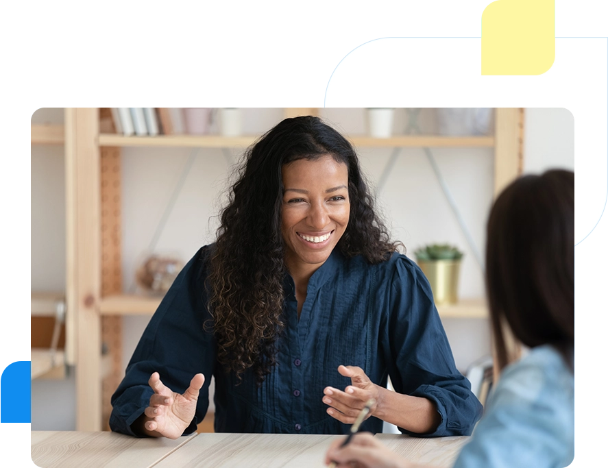 A woman sitting at a table talking to another person.