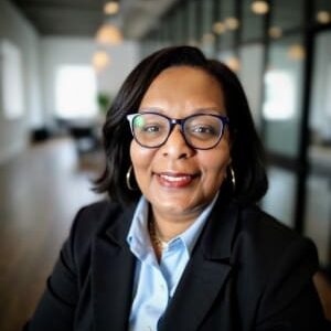 Professional woman with glasses smiling in an office setting.